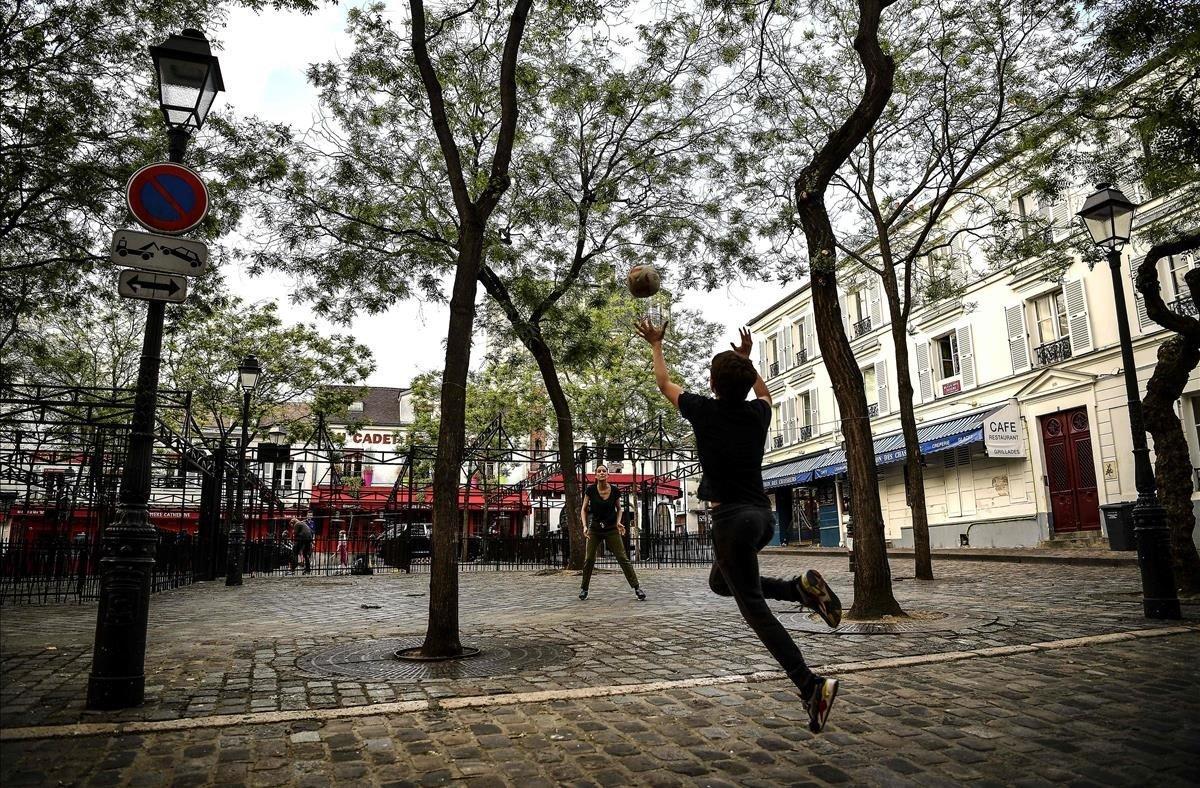 Una madre y su hijo juegan al rugby en la Place du Tertre, una plaza habitualmente repleta de pintores y artistas ubicada en la cima de la colina de Montmartre.