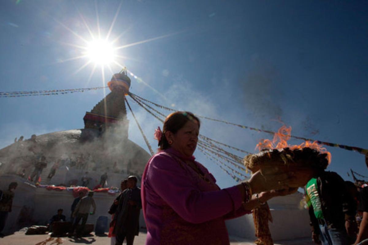 Una dona crema encens mentre resa davant l’estupa budista Bauddhanath, a Kàtmandu (Nepal).