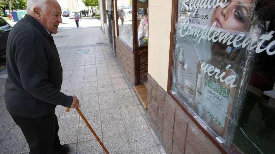 Un hombre mira la luna rota de una perfumería de la calle Pelayo, en Versalles.