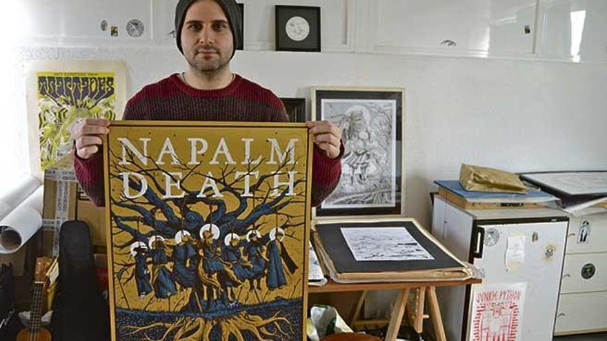 Gonzalo Aeneas en su estudio sosteniendo el cartel que realizó para un concierto de Napalm Death.