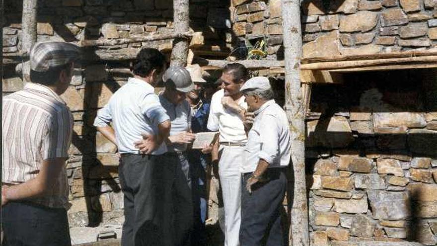 Miguel Fisac (con casco) examina y documenta un documento junto al alcalde de Pumarejo, Isaías Galende, y otros vecinos