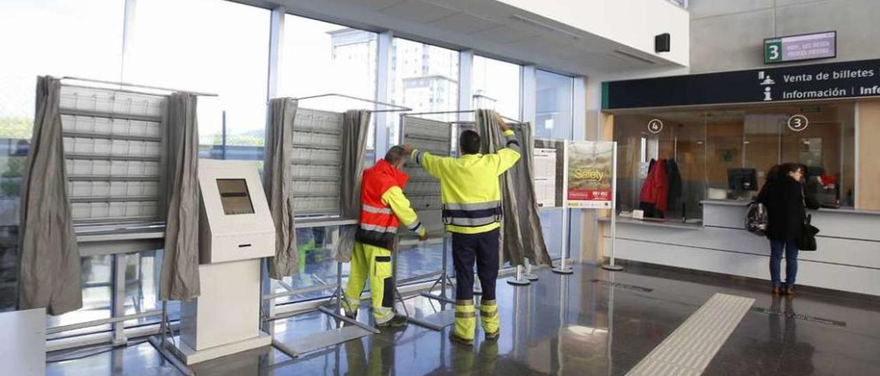 Operarios instalando las cabinas de voto, ayer por la mañana en la estación de tren de Urzáiz, en Vigo. // Ricardo Grobas