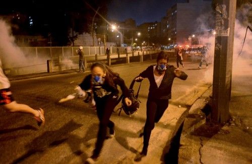 Protesters run from tear gas shot by riot police in Rio de Janeiro