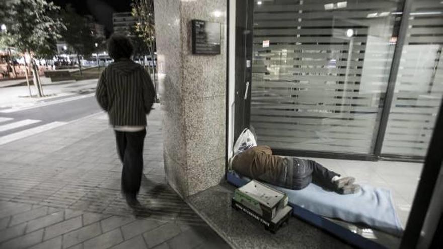 Dos personas sin techo se refugian en los cajeros de la ciudad para cobijarse del frío y poder dormir.