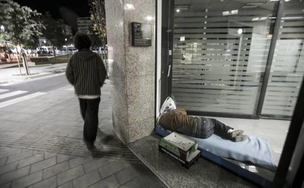 Dos personas sin techo se refugian en los cajeros de la ciudad para cobijarse del frío y poder dormir.
