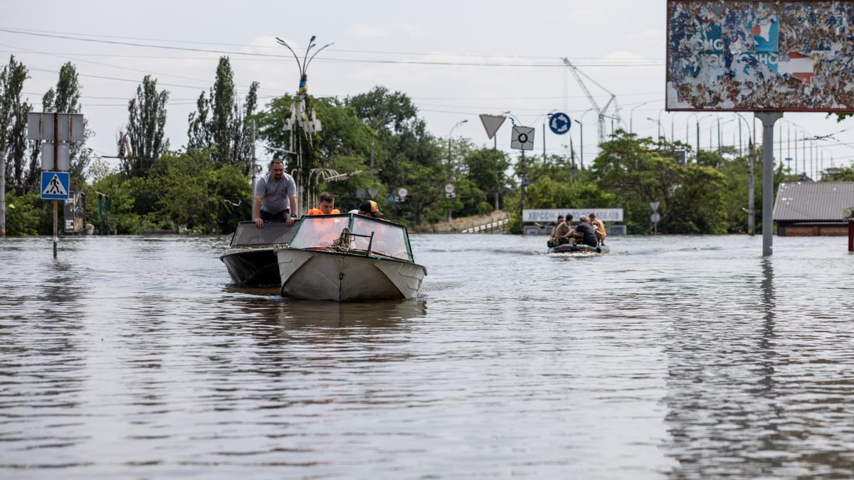 Residentes y trabajadores de los servicios de rescate usan barcas para moverse en una zona inundada de Jersón, Ucrania.