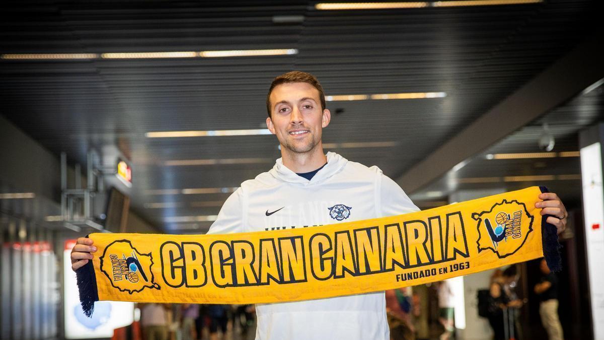 Joe Cremo posa en la terminal de llegadas del aeropuerto de Gran Canaria con una bufanda del CB Gran Canaria