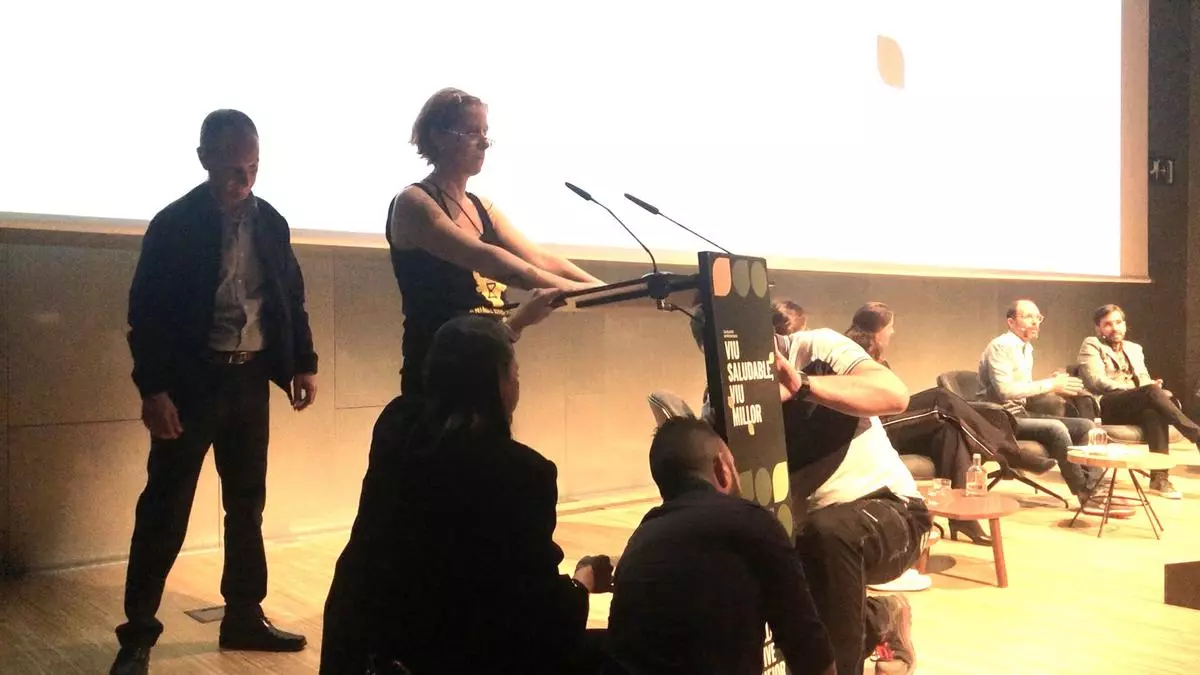 Una activista interrumpe un acto de Yolanda Díaz, Garzón y Colau y se pega al atril con pegamento