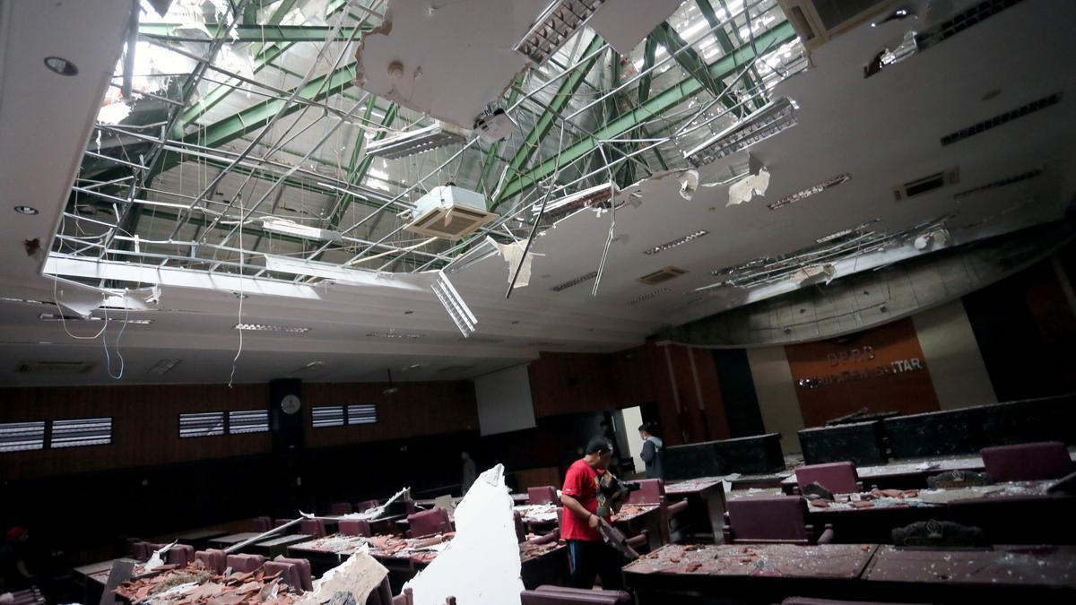 Un hombre recoge los trozos de un edificio dañado por el terremoto en Indonesia