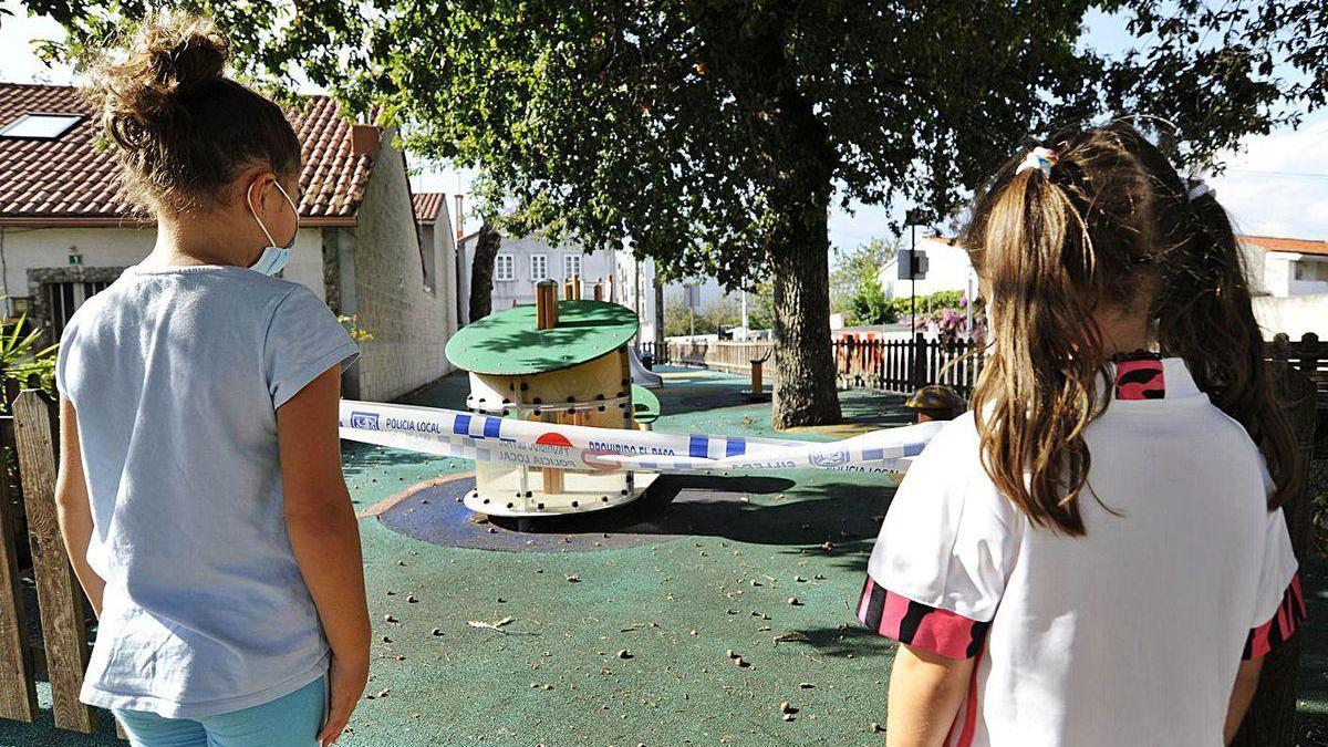 Un par de niñas, ayer por la tarde, ante un parque clausurado en A Bandeira.