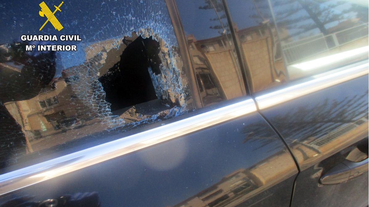 Uno de los coches con la luna rota tras ser vandalizado.