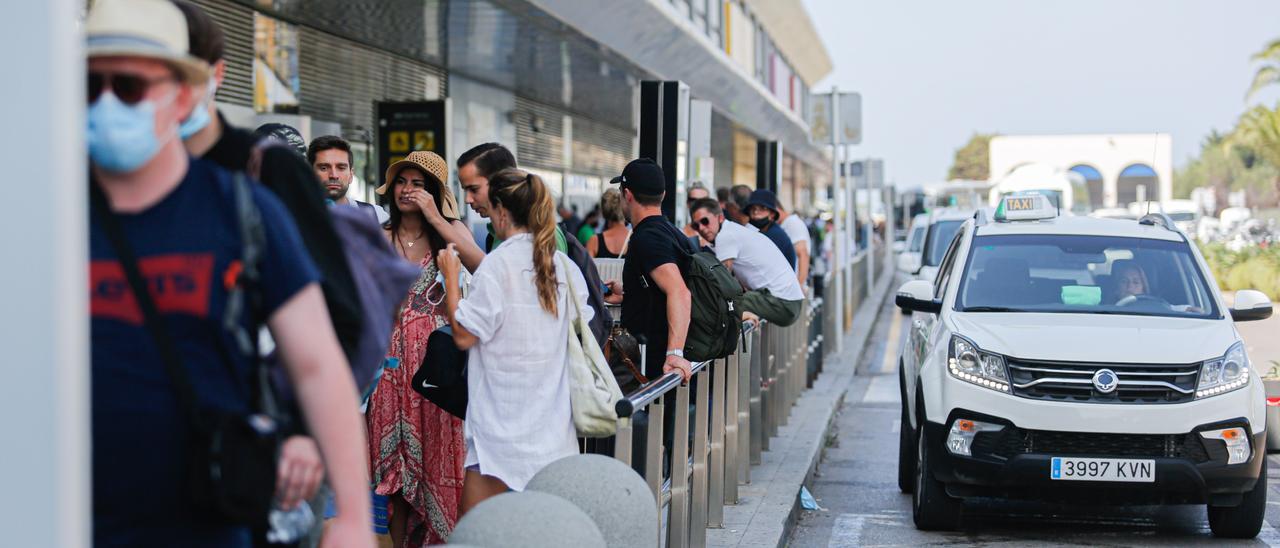 Cola de turistas esperando un taxi en la parada del aeropuerto.