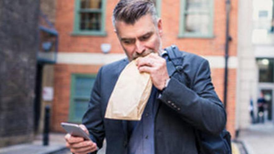 Un trabajador consulta su móvil mientras come.