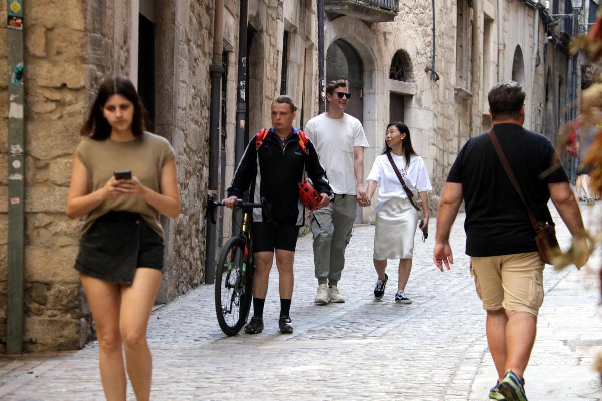 Un ciclista anant a peu i amb la bici al costat pel carrer de la Força de Girona.