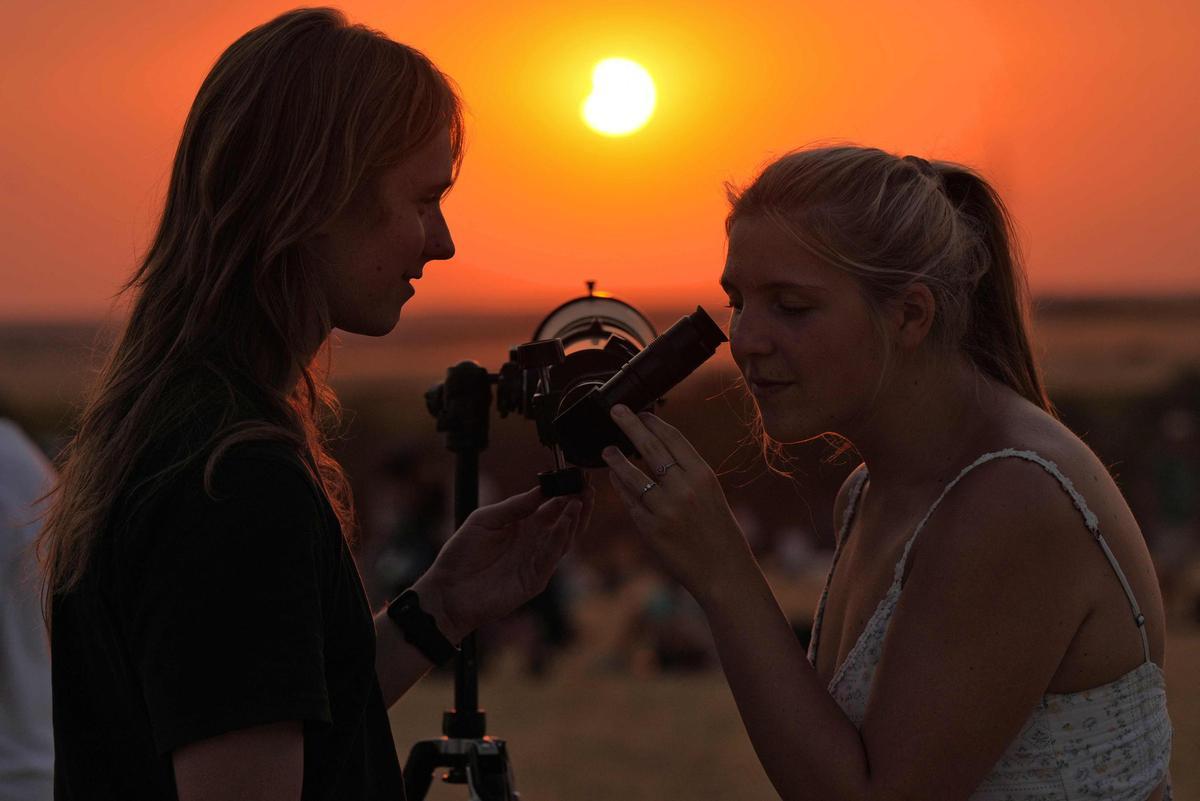 Dos mujeres observan cómo la Luna se retira de delante del Sol, hacia el final del eclipse, en la localidad de Lodoso, Burgos.