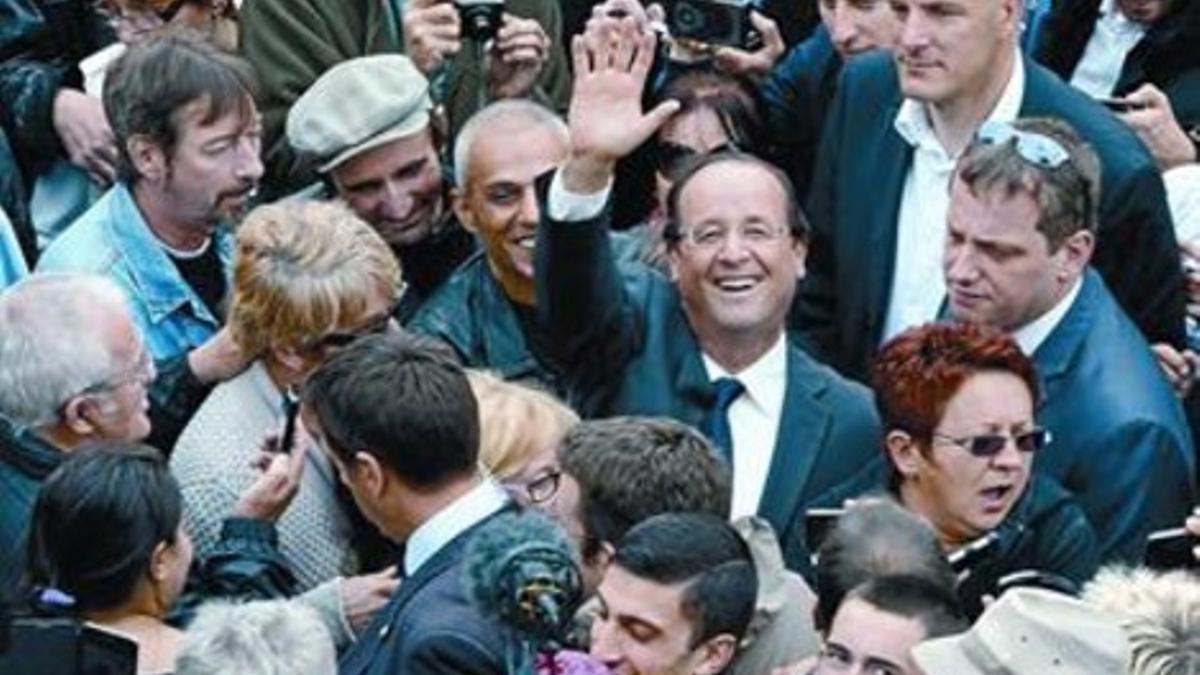 Hollande (centro) saluda en medio de una multitud en un mercado de Tulle.