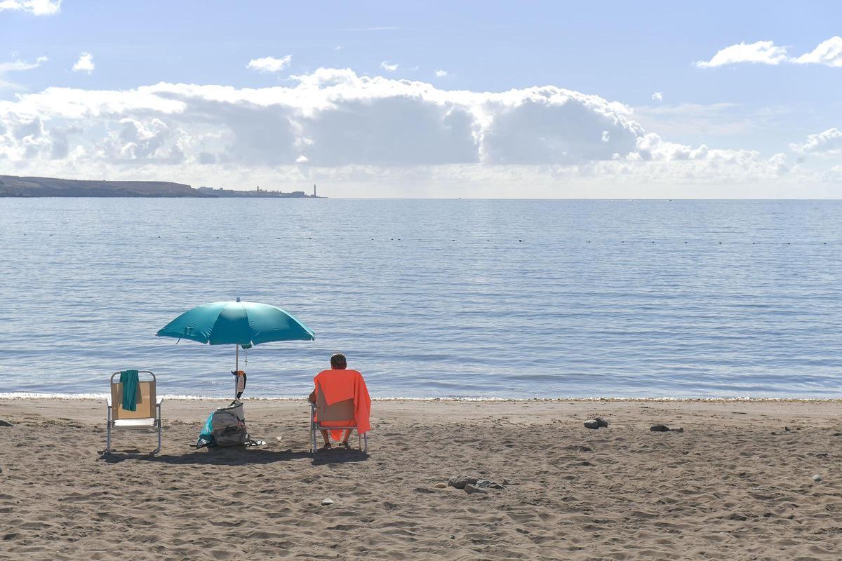 Una bañista observa la marea en la playa de El Pajar.
