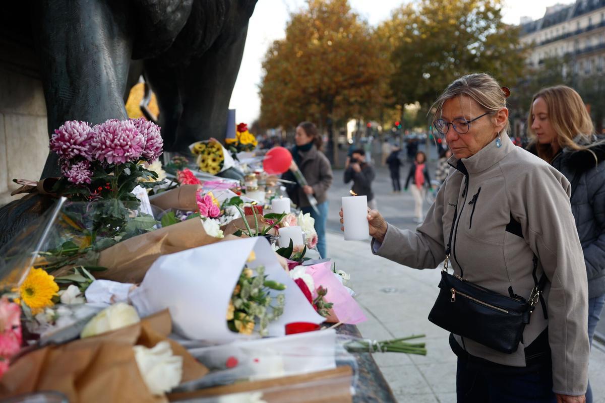 Una mujer coloca una vela en recuerdo de los fallecidos en los atentados de 2015 en un memorial en la plaza de la República de París, el pasado domingo.