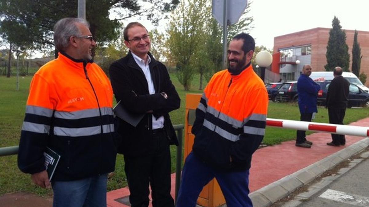 El candidato de ICV-EUiA bromea con dos trabajadores, este viernes, durante la visita a la planta de Alstom.