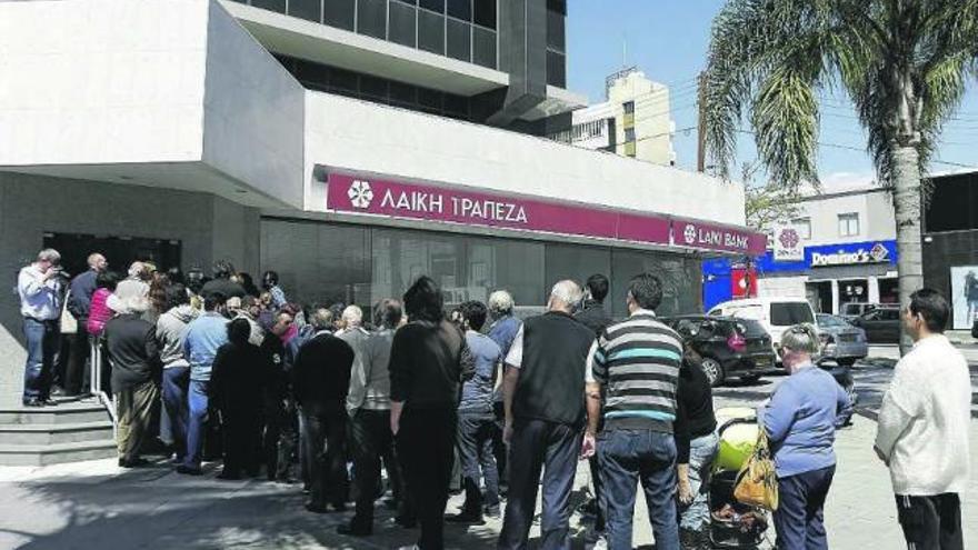 Ciudadanos chipriotas hacen cola ante una oficina bancaria a la espera de su apertura.  // Stringer