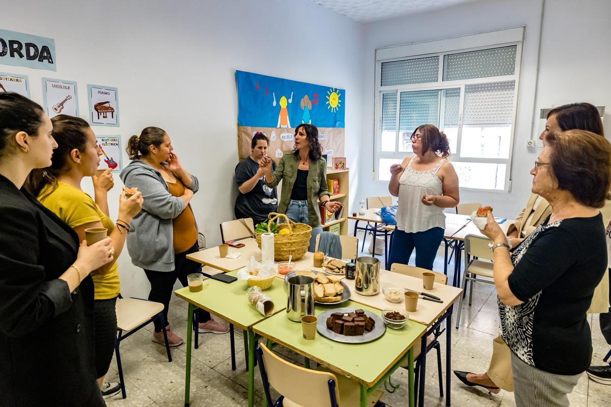 Un grupo de madres escucha las explicaciones de una experta en nutrición mientras también toman un desayuno con productos más sanos.