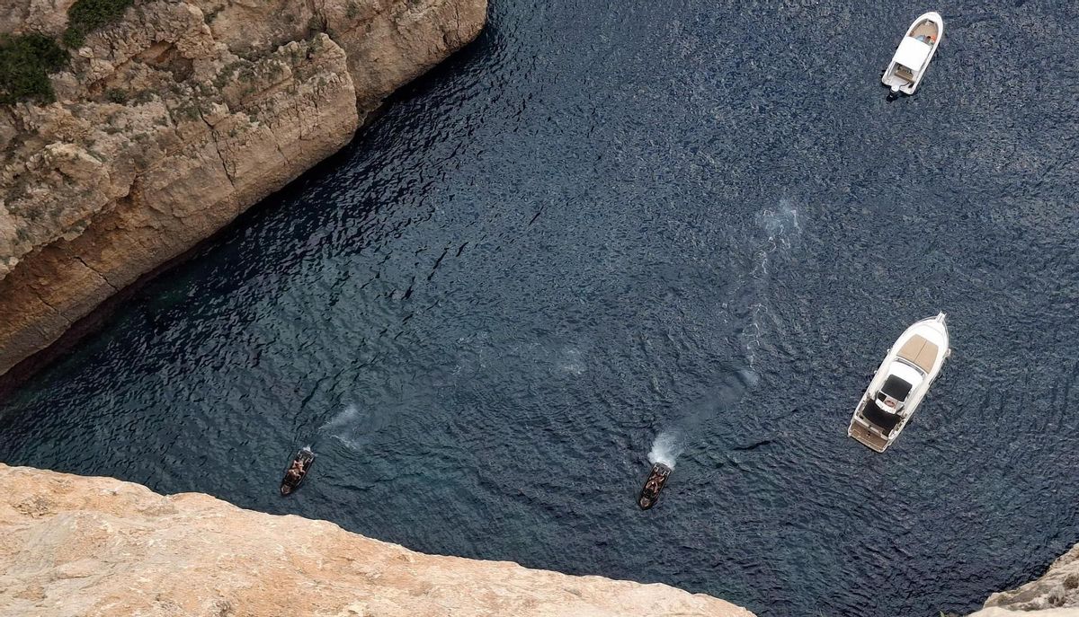Motos y embarcaciones, arrimadas al acantilado del Cap de la Nau.