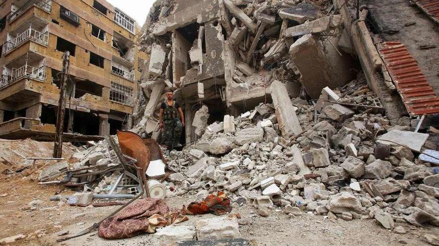 Un soldado gubernamental sirio entre las ruinas de un edificio en la localidad de Zamalka, en Guta Oriental. // AFP