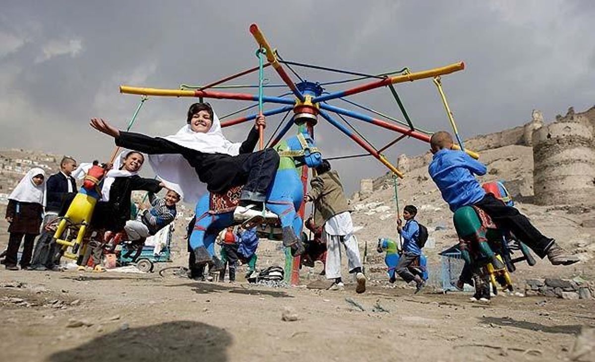 Nens afganesos munten en uns cavallets a Kabul (Afganistan).