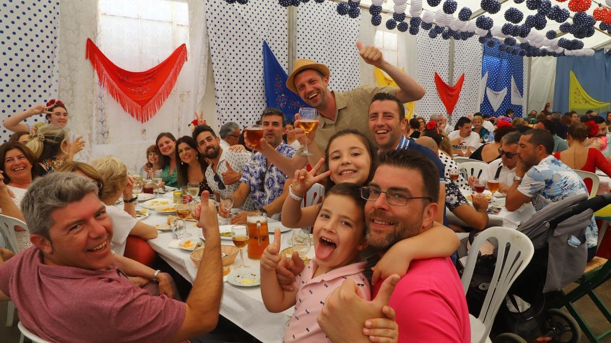 Un grupo de amigos disfruta con sus hijos de un acomida en una caseta.