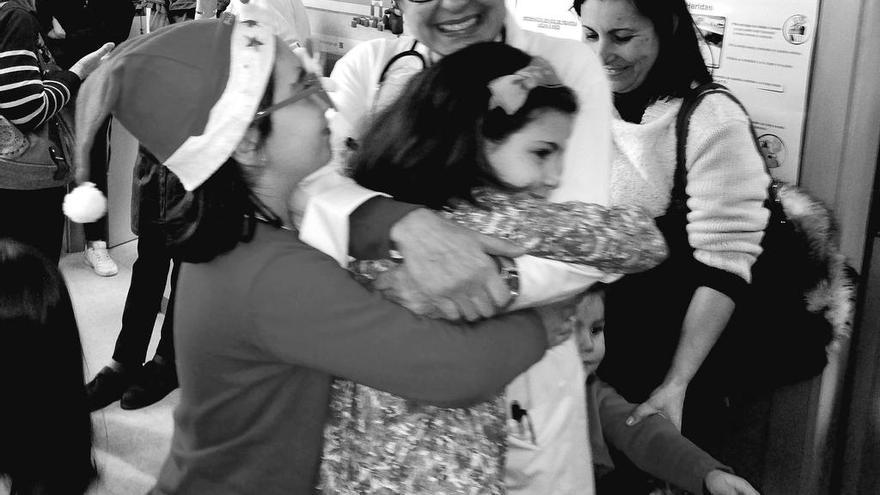Teresa Valls abraza a dos niñas tras el villancico sorpresa que le cantaron pacientes y compañeros en A Xunqueira. // N.P.