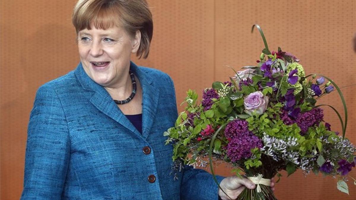 Merkel sostiene un ramo de flores al llegar a la cancillería para una reunión del Gobierno, ayer