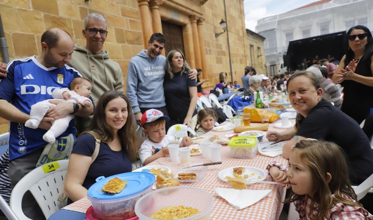 Teresa Álvarez, a la derecha, detrás de la niña Carlota Prieto, junto a un grupo de amigos y familiares, durante la comida en la calle. | Analía Pello