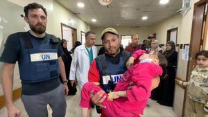 Eliezer en uno de los pasillos del Nasser Center con una niña en brazos y otro cooperante a su lado