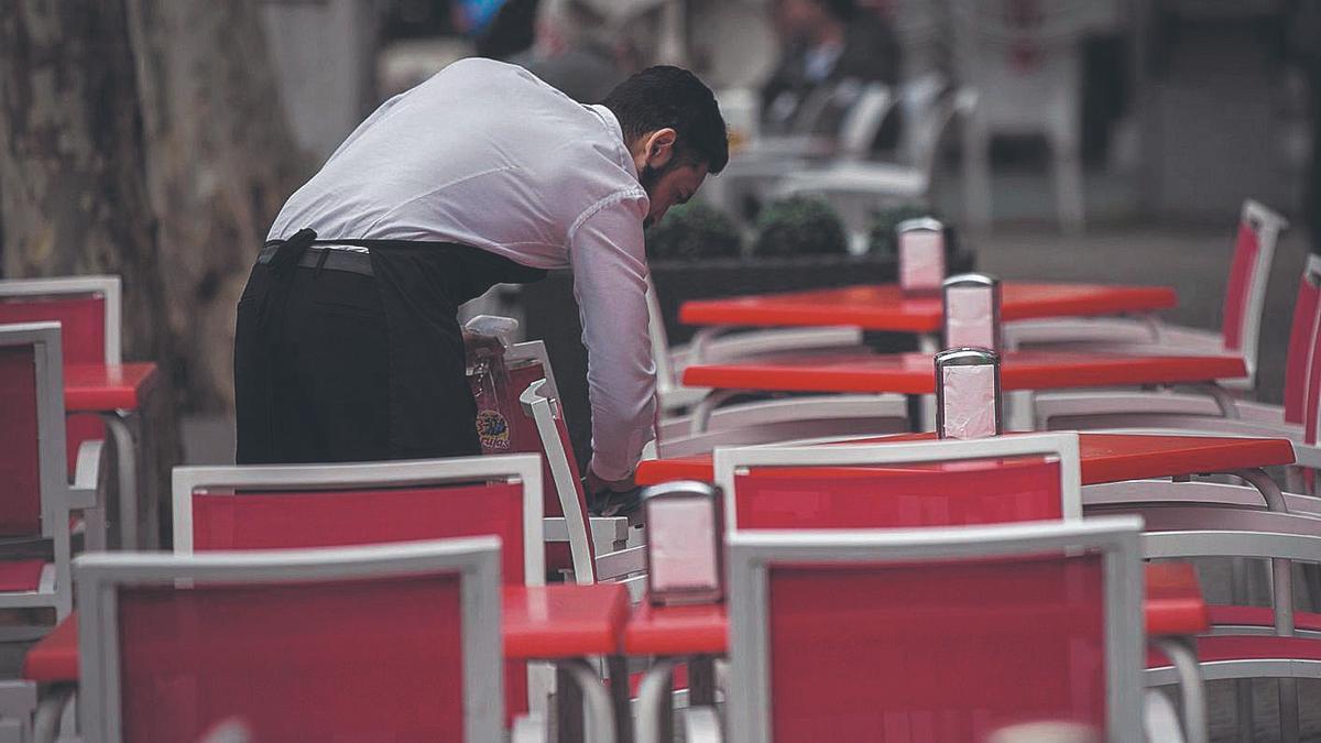 Un camarero limpia las mesas de una terraza en Sevilla.