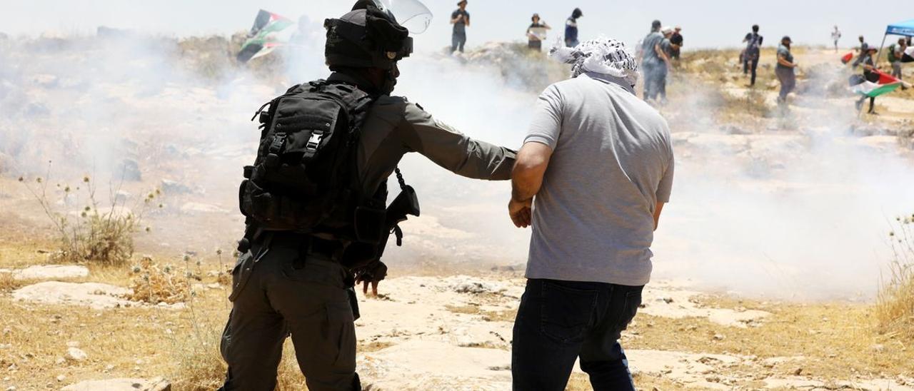 Un policía israelí carga contra un palestino.