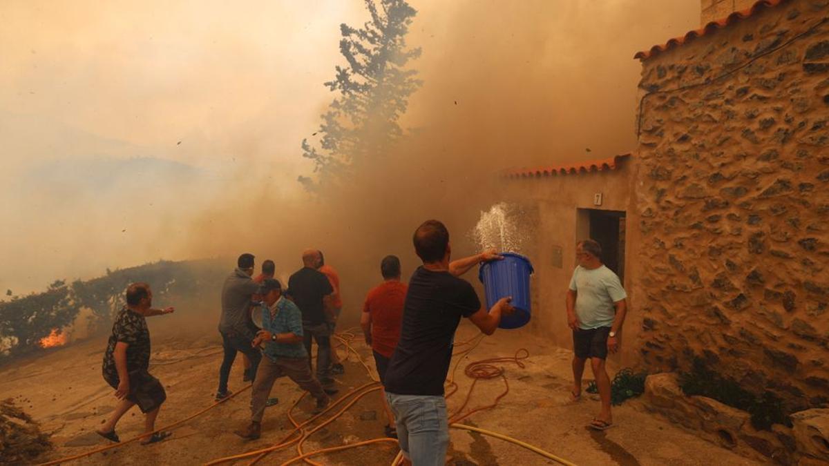 Los vecinos de Añón tratan de evitar que el fuego llegue a las primeras casas del casco urbano con cubos de agua y mangueras.