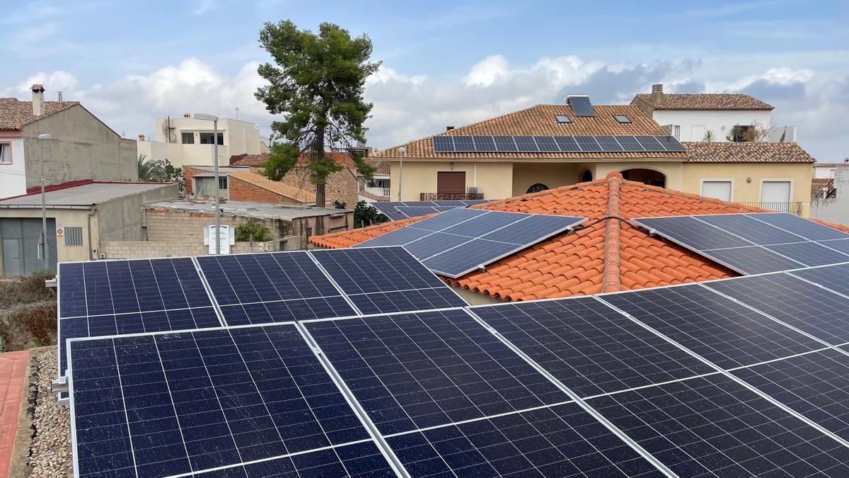 Placas solares sobre la cubierta del colegio de Potries y, al fondo, en una vivienda privada