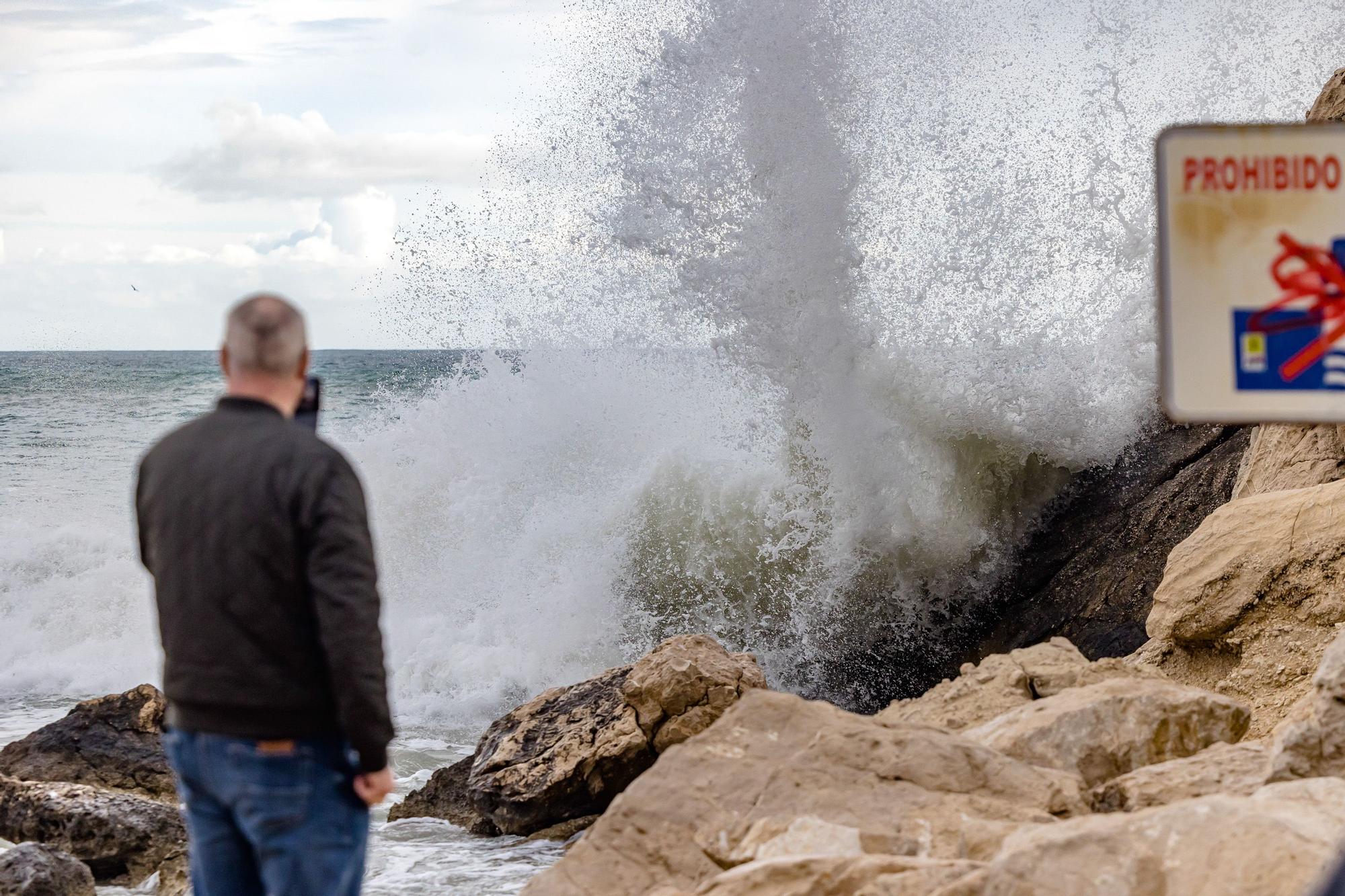 Turistas y paseantes observan el temporal de mar en la Cala de Finestrat