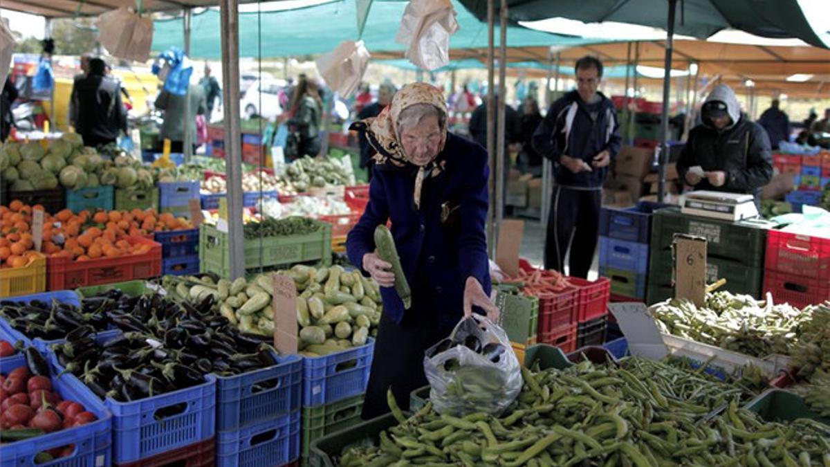 Una anciana compra en un puesto de verduras de un mercado de Nicosia, ayer.
