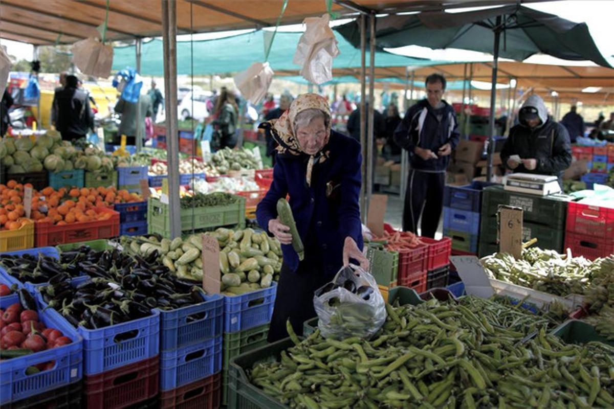 Una anciana compra en un puesto de verduras de un mercado de Nicosia, ayer.