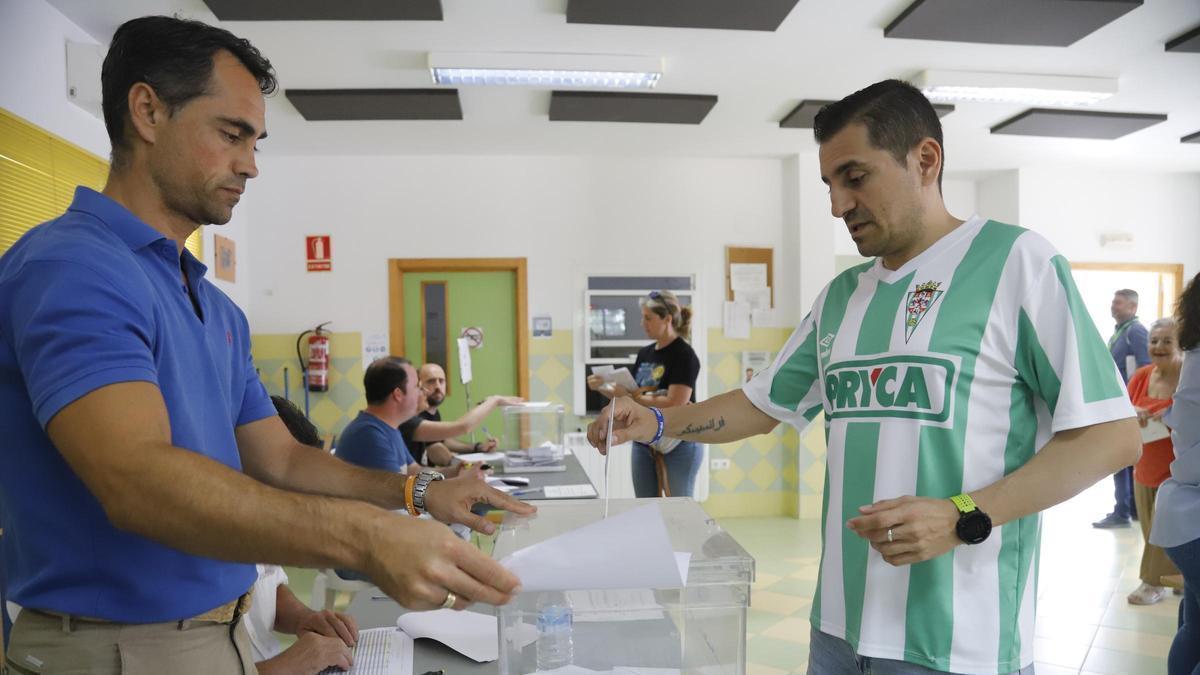 Un seguidor del Córdoba CF vota en unas recientes eleciones con la camiseta blanquiverde.