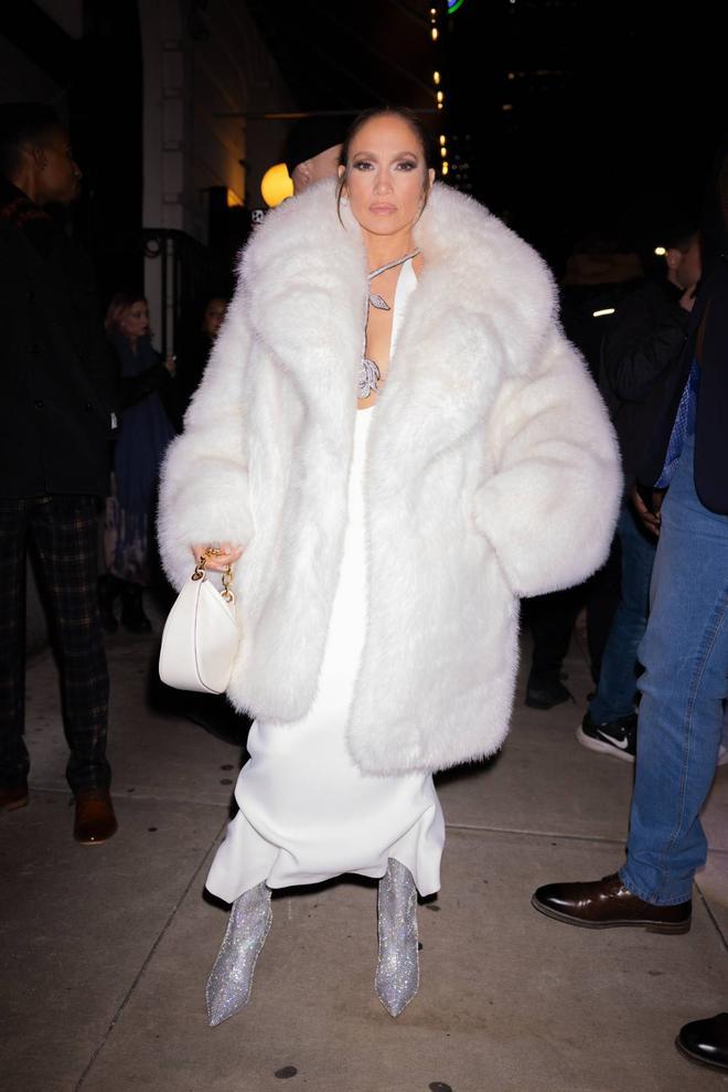 Jennifer Lopez con abrigo de pelo, vestido blanco y botas brillantes