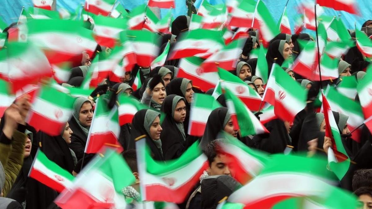 Estudiantes ondean banderas iranís durante la ceremonia de conmemoración de la revolución.