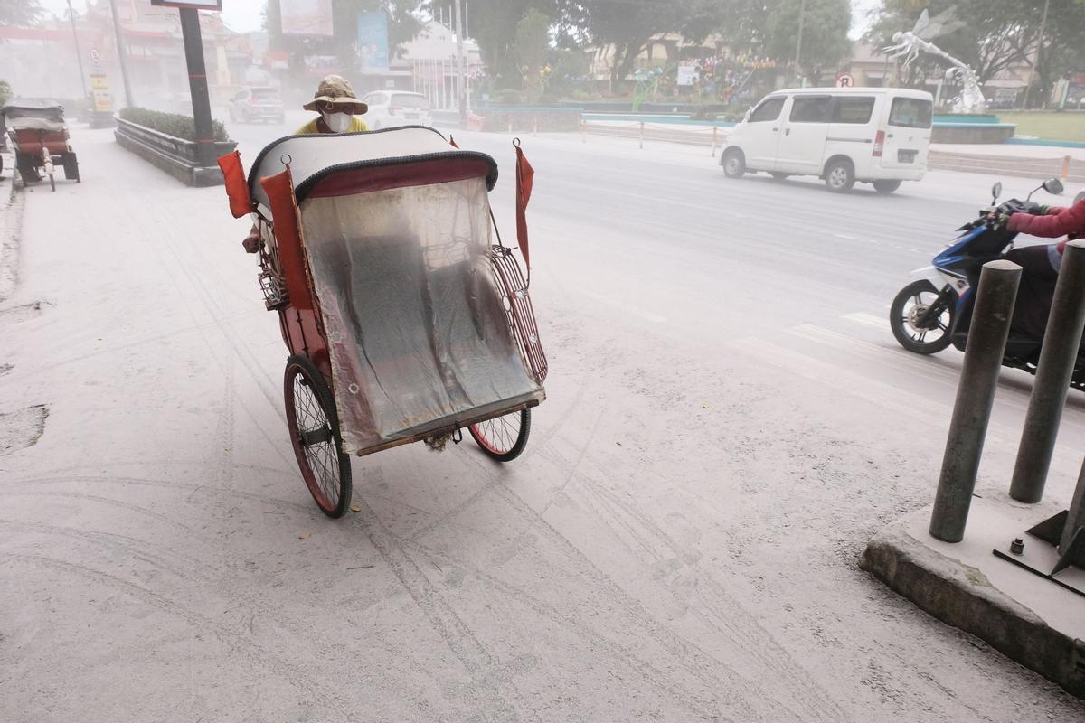 Un triciclo pasa por una carretera cubierta por cenizas de la erupción del volcán Monte Merapi de Indonesia, en Magelang, provincia de Java Central, Indonesia