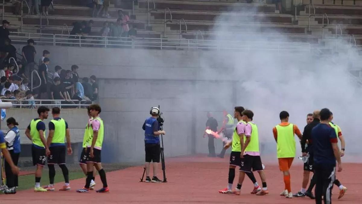Los jugadores del Badalona durante la pausa de hidratación entre el humo de las bengalas.
