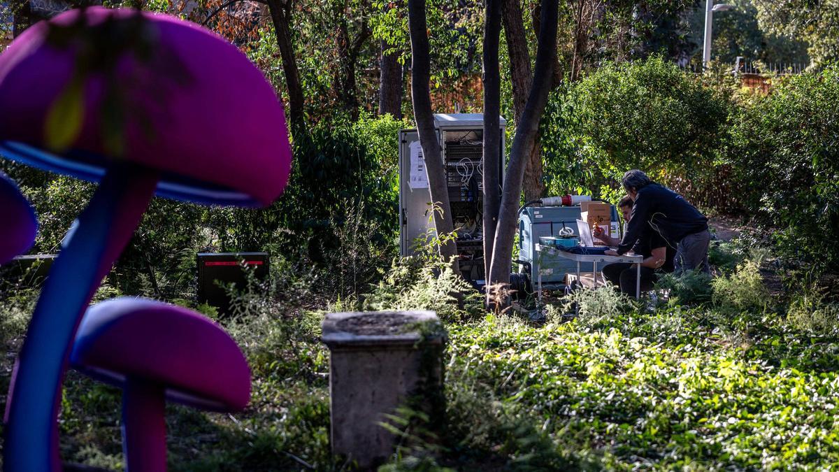 Dos trabajadores preparando la instalación lumínica del espectáculo Natura Encesa, en los jardines de Torre Girona, en Barcelona.