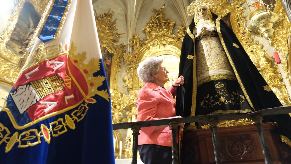 La hermana mayor de la cofradía coloca el manto a la virgen.