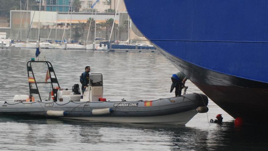 Una lancha de la Guardia Civil, junto al buque, durante las maniobras