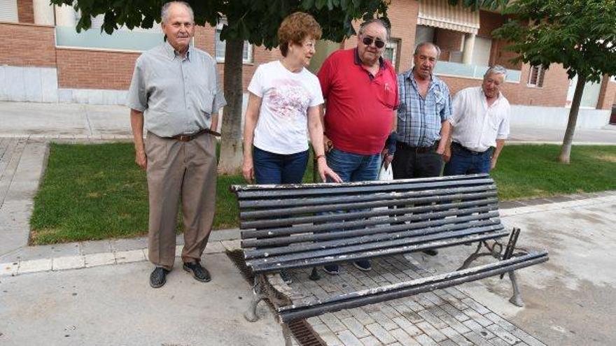 Alguns dels veïns afectats per l&#039;atac al mobiliari urbà mostren un dels bancs malmesos