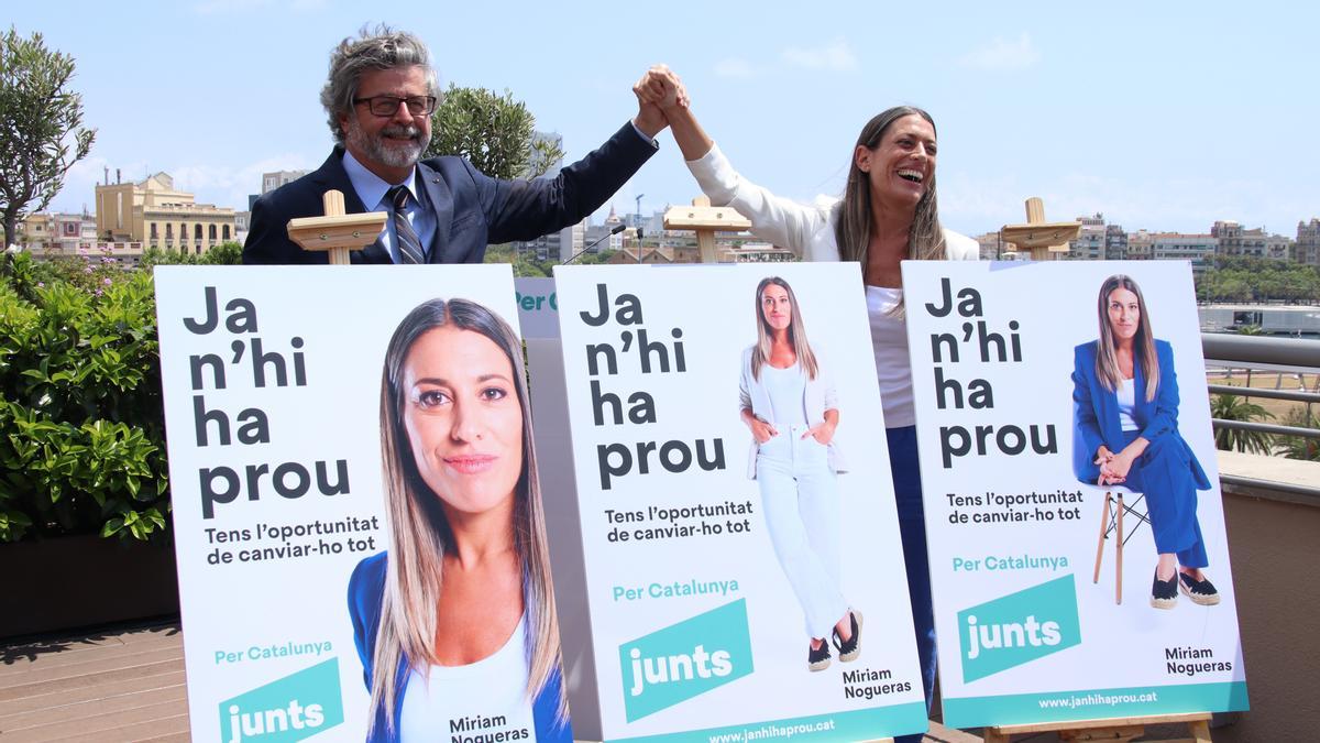 Míriam Nogueras i Toni Castellà amb les mans agafades darrere els cartells de campanya.